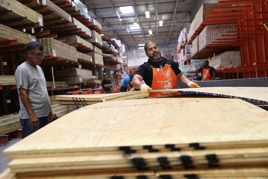 A Home Depot employee loads a stack of plywood.