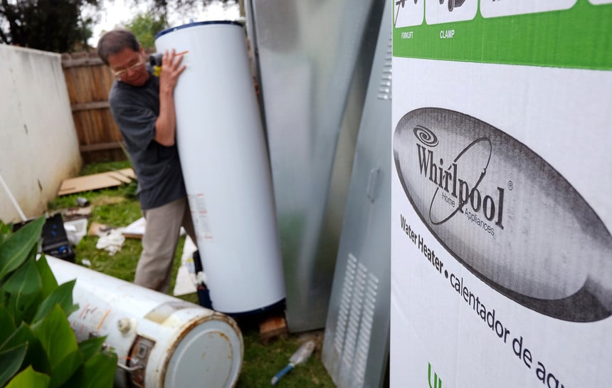 A repairman installs a water heater at a Los Angeles home. California regulators are poised to approve a plan that would phase out some natural has appliances.