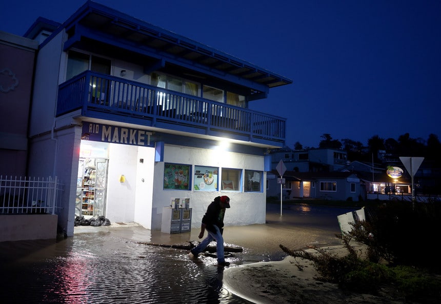 A customer walks through floodwater while departing a store on Jan. 10 in Aptos, Calif.
