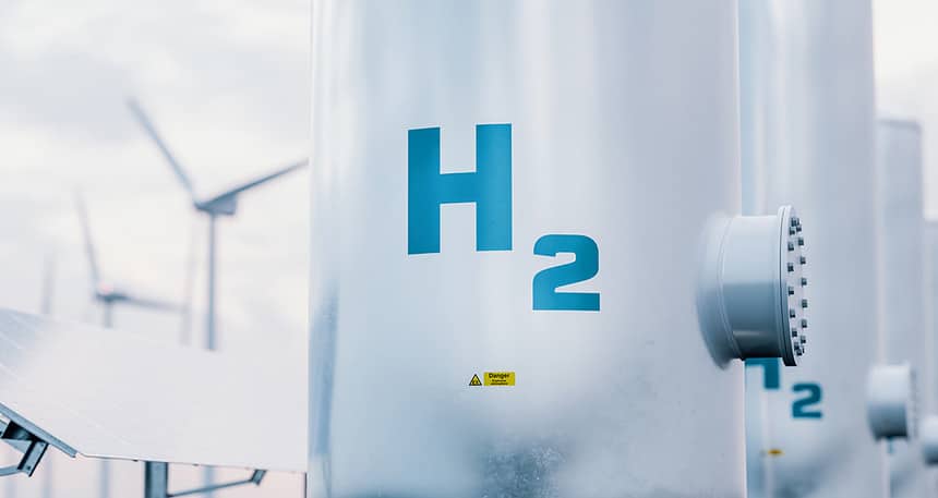 Rendering of hydrogen energy storage gas tanks with solar panels and wind turbines in background.